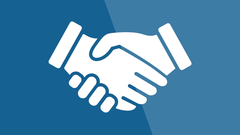 Stock image of two hands shaking over a two-toned blue background. 