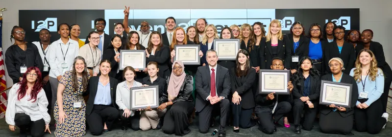 Image of recent Invent 2 Prevent high school and college winners standing on the I2P competition stage holding their certificates.