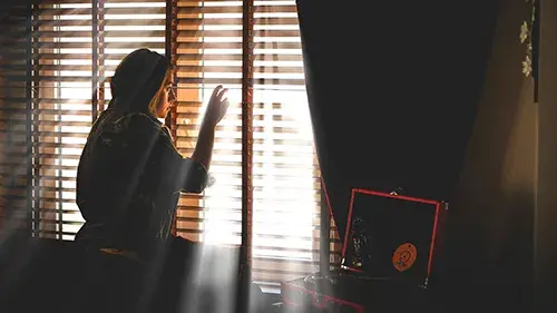 Woman peeking through blinds