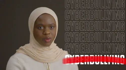 Screenshot image of a female being interviewed, with the words "Cyberbulling" across the screen, with one "Cyberbullying" crossed out.