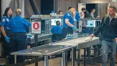 A photo of passengers at the airport going through the security line. 